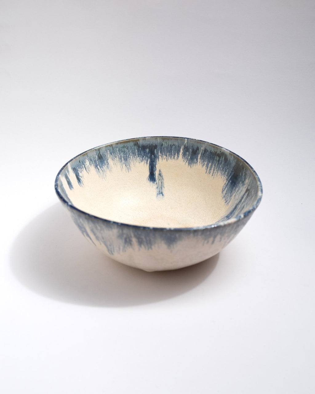 Big Ceramic bowl with blue and white glaze on a light gray background