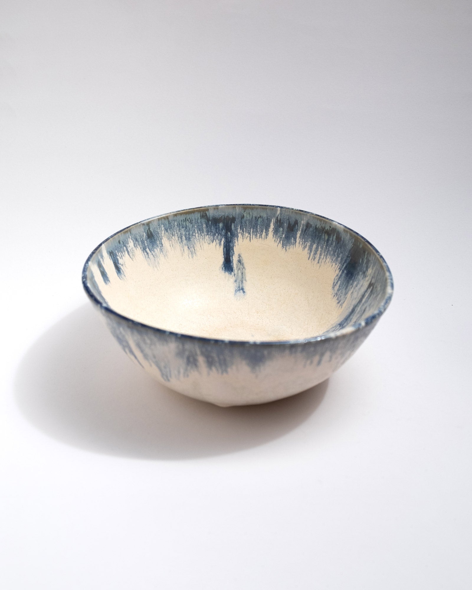 Big Ceramic bowl with blue and white glaze on a light gray background