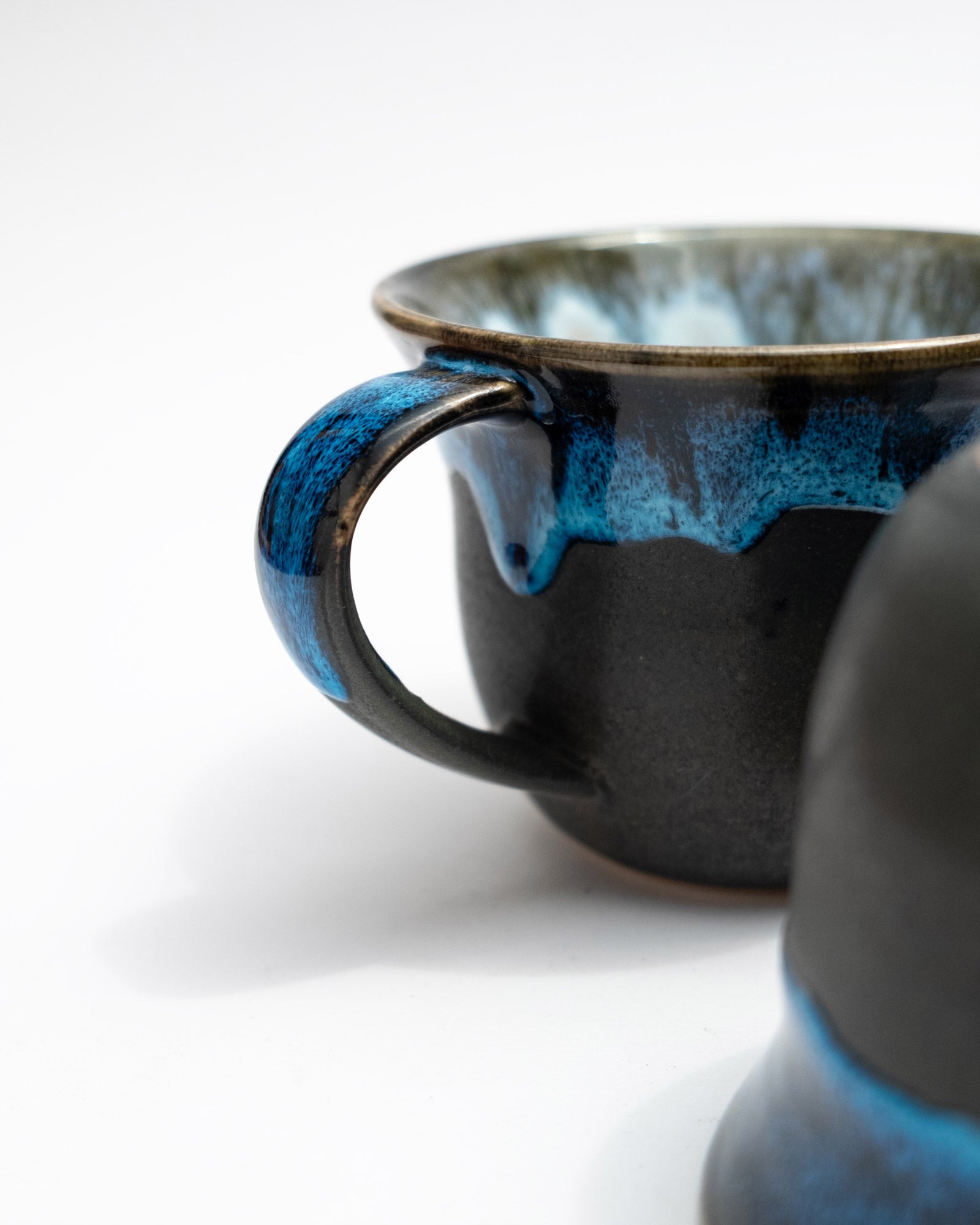 Black ceramic mug with blue handle on a white background