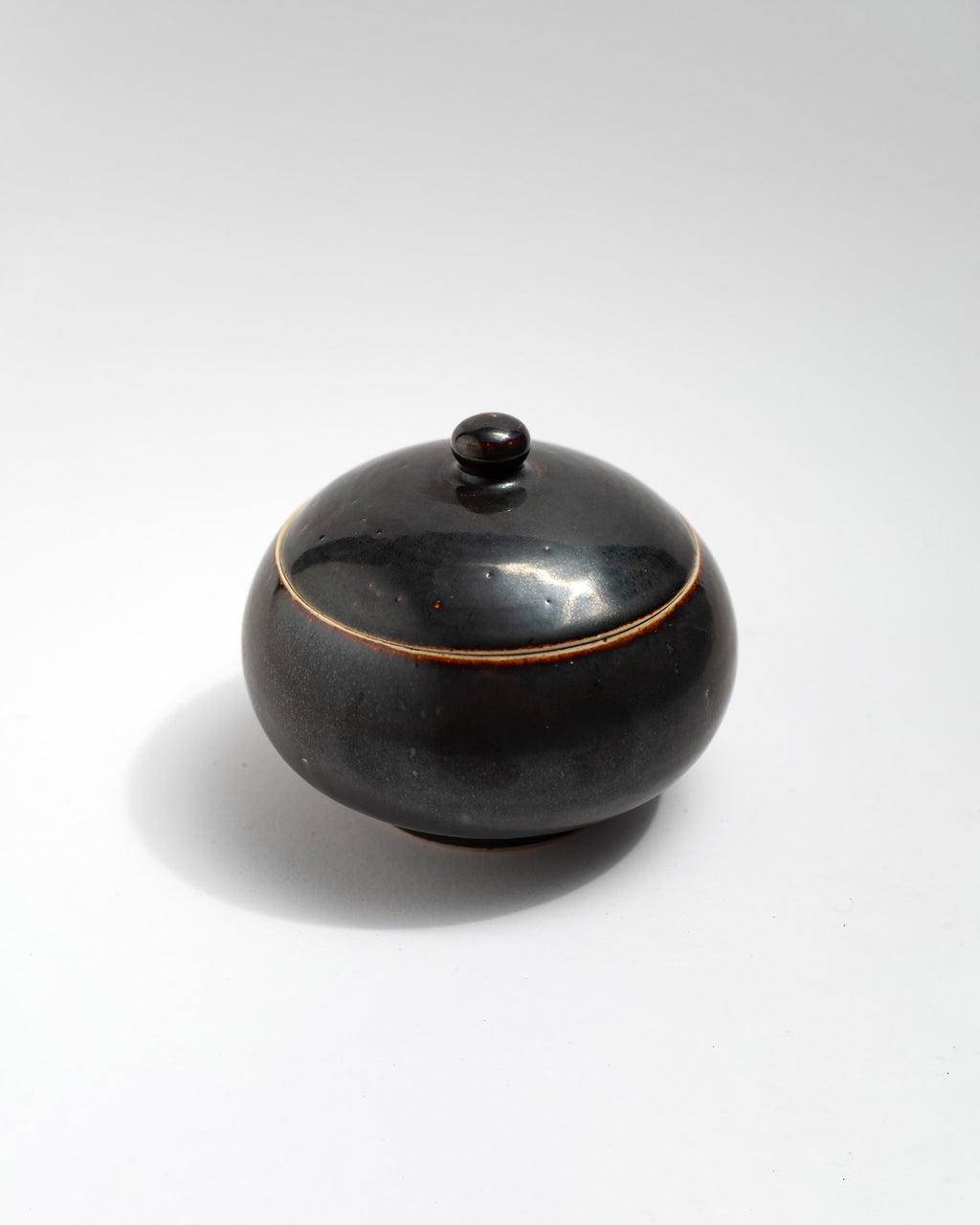 Black ceramic jar with a lid on a white background