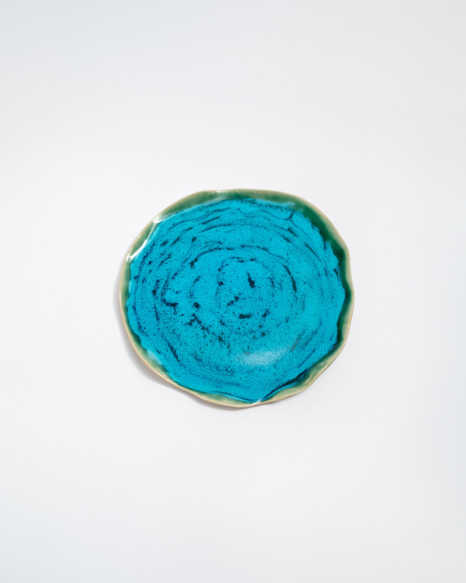 Round turquoise ceramic dish on a white background