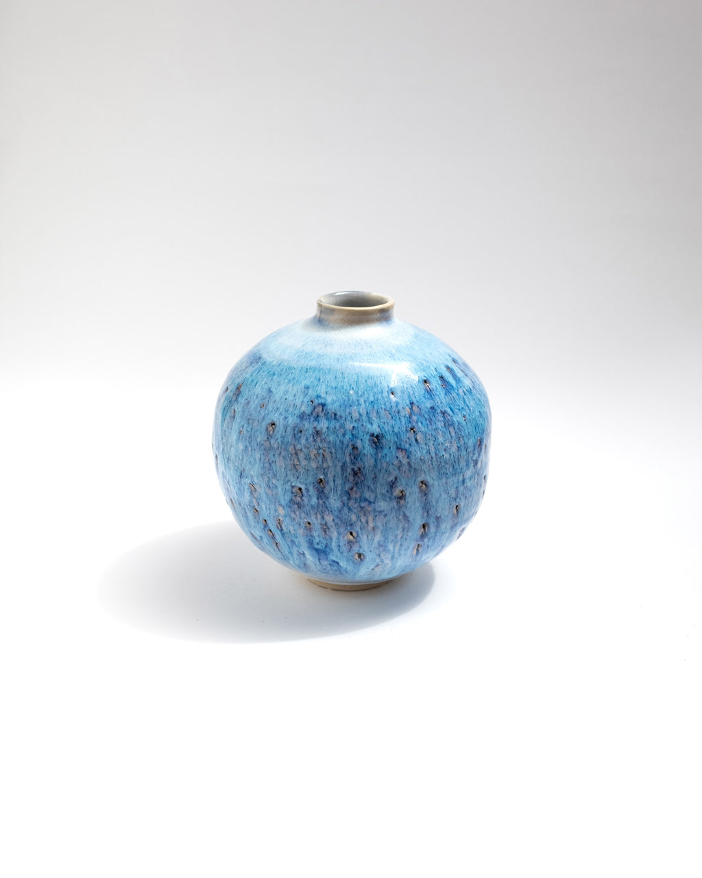 Blue ceramic vase with speckled pattern on a white background, handmade in Italy