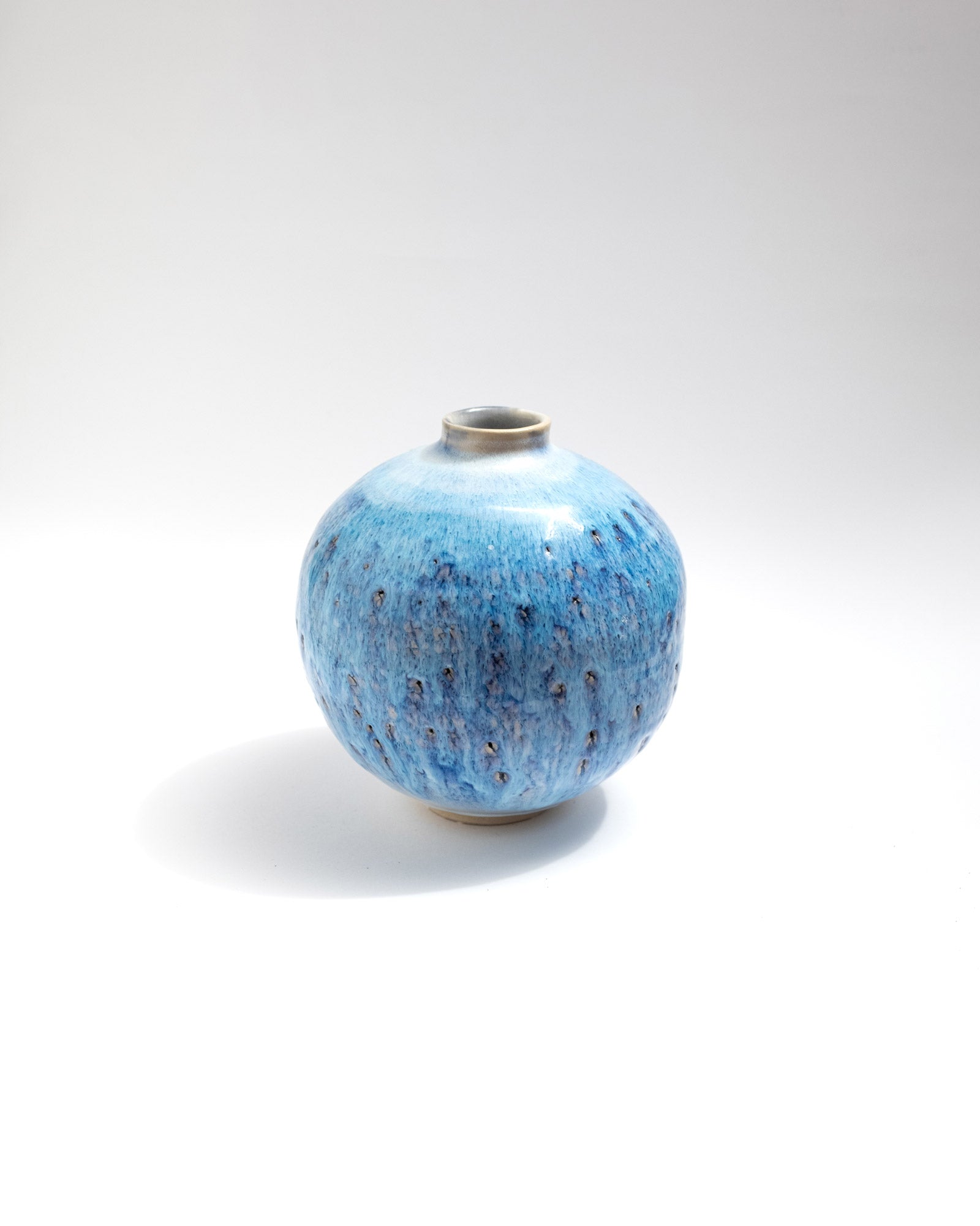 Blue ceramic vase with speckled pattern on a white background, handmade in Italy