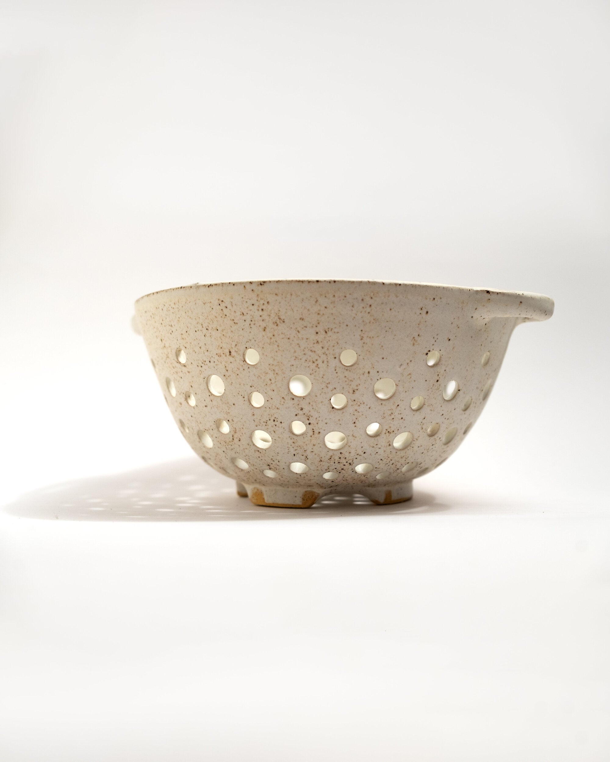 Speckled ceramic colander on a white background