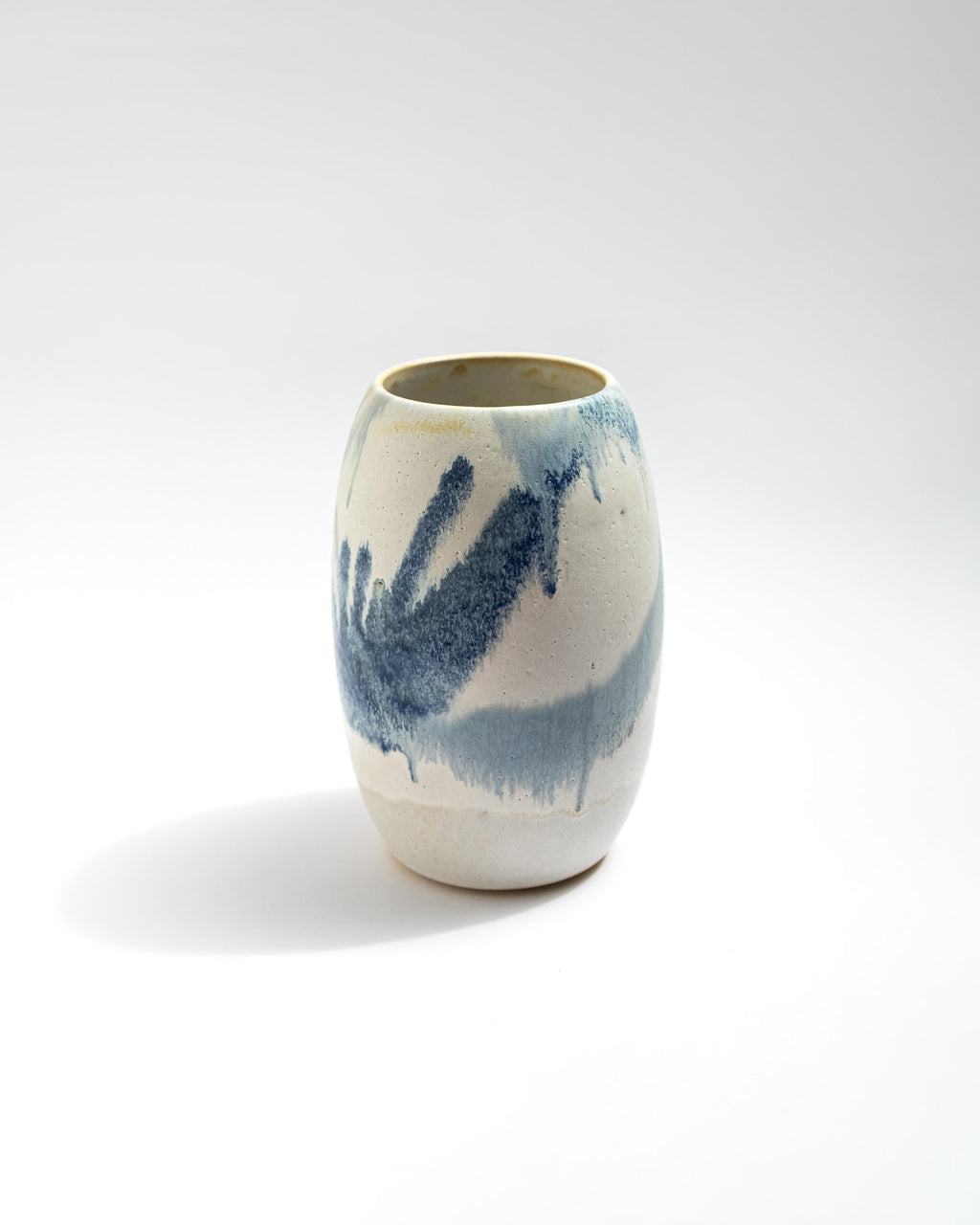 Ceramic white vase with blue abstract design on a white background