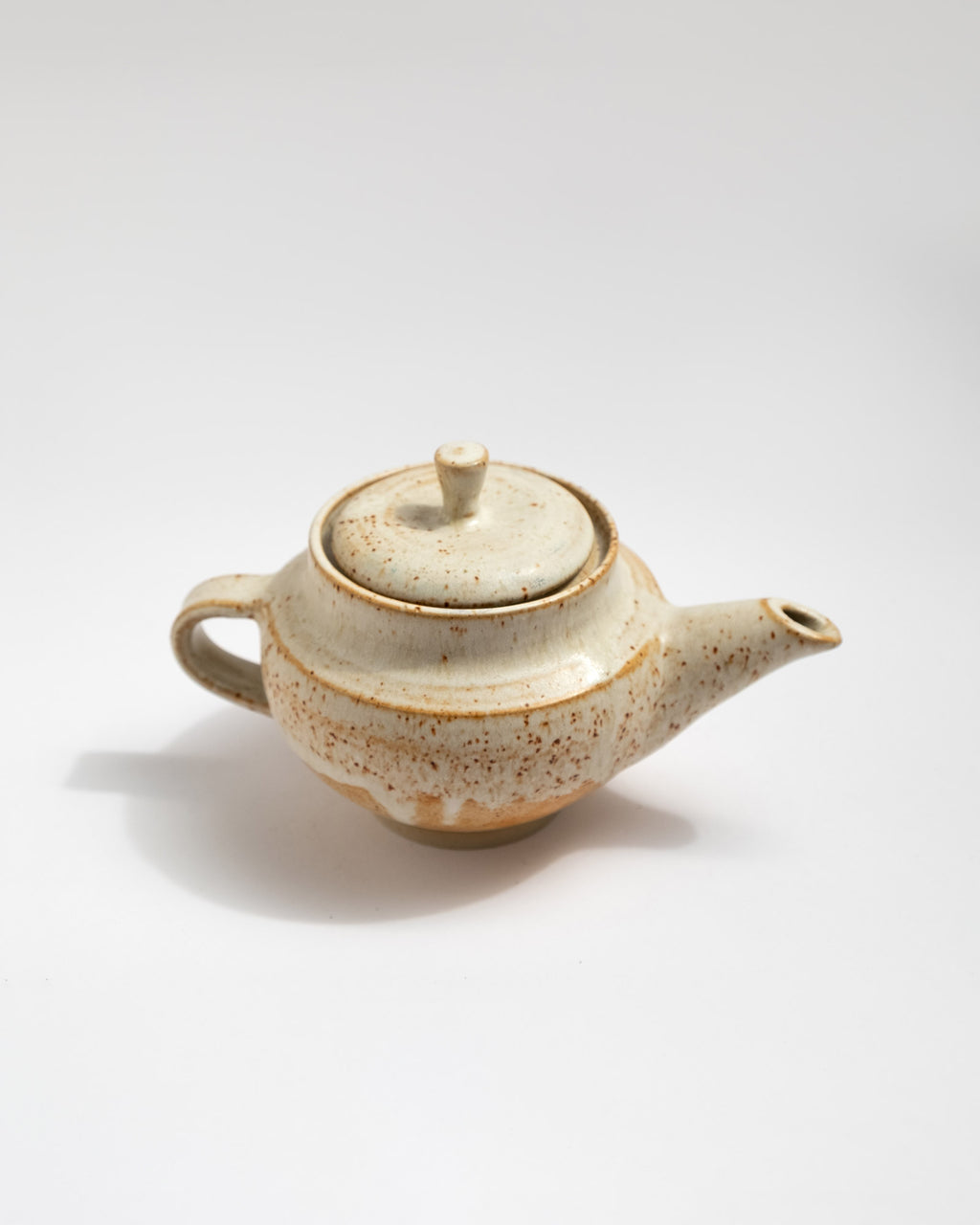 Ceramic handmade teapot with speckled pattern on a white background