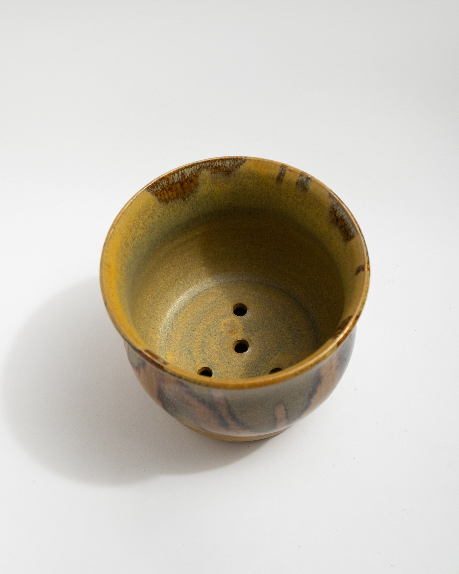 Ceramic plant pot with brown and green glaze on a white background