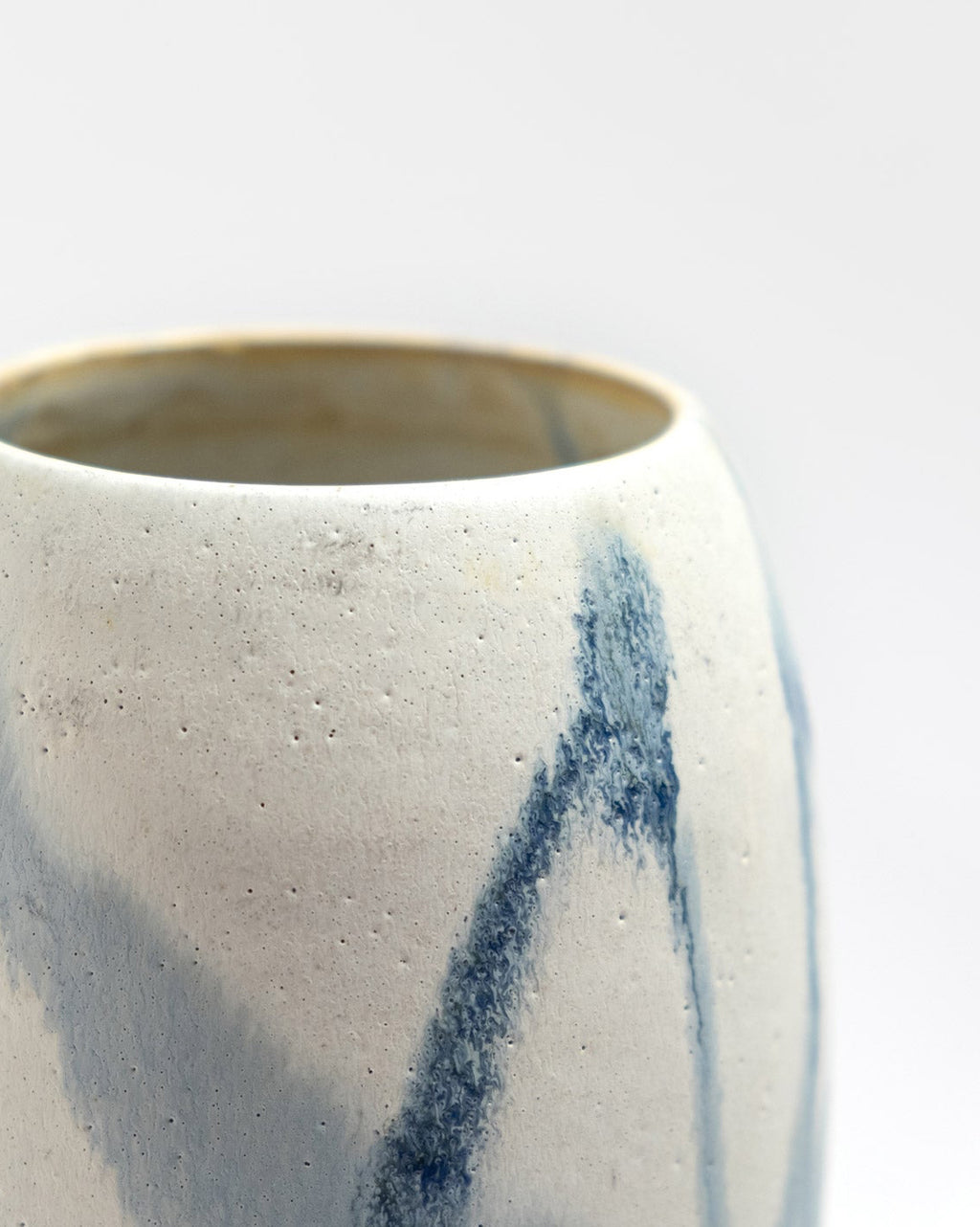 Ceramic vessel with blue abstract design on a light gray background