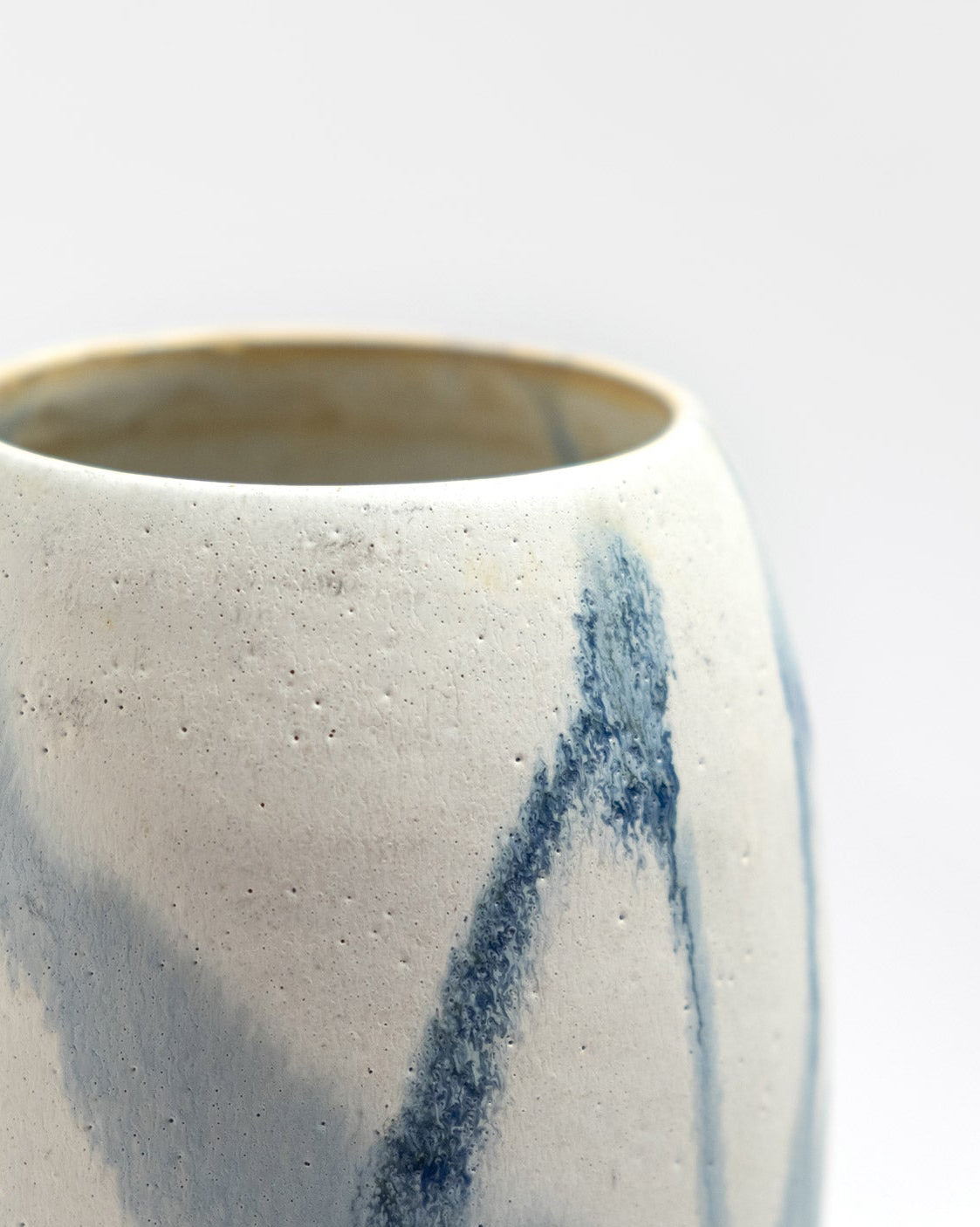 Ceramic vessel with blue abstract design on a light gray background