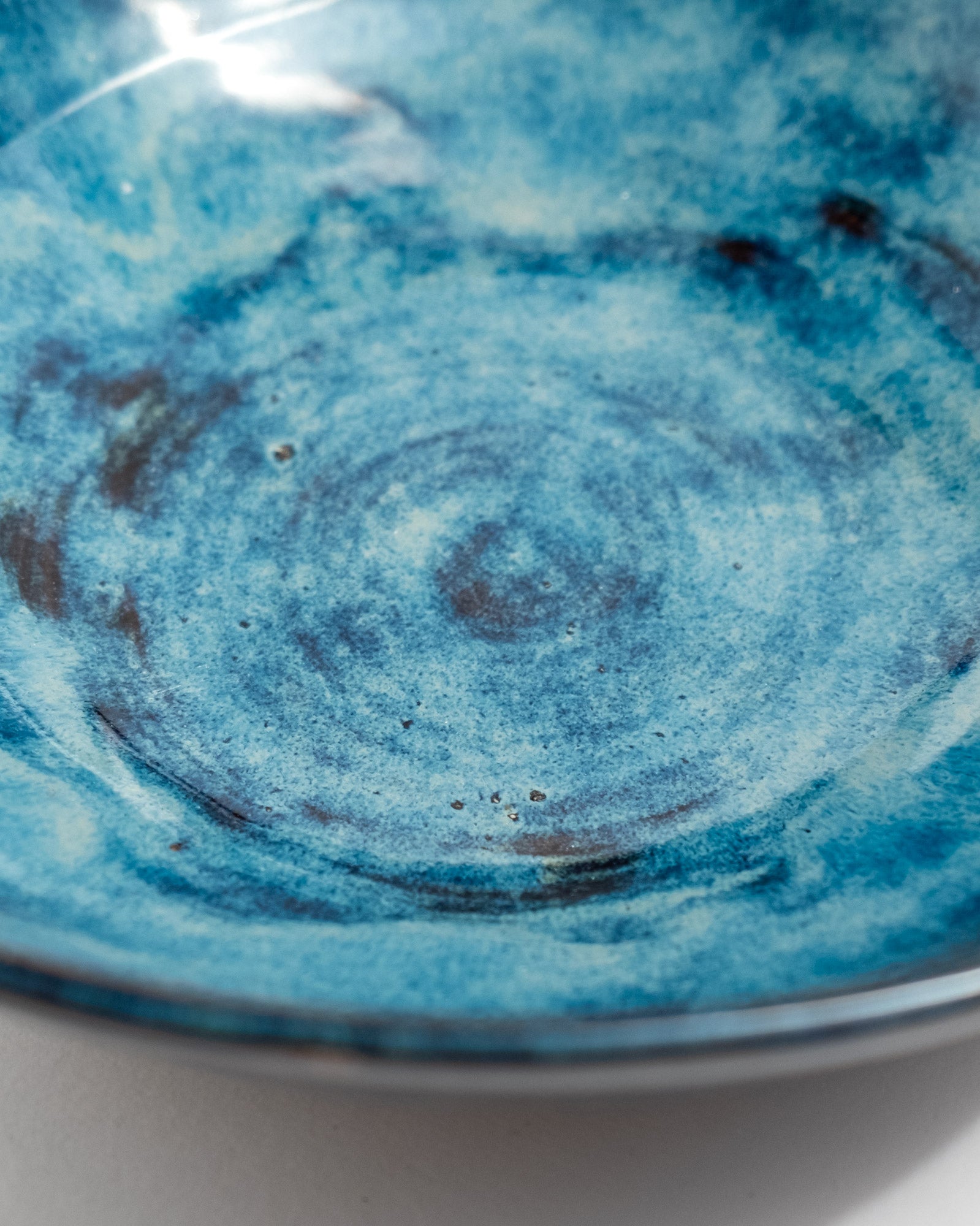 Close-up of a blue ceramic bowl with swirling patterns, handmade in Italy