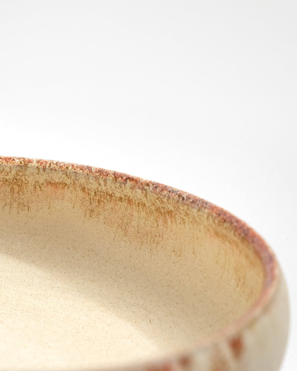 Close-up of a ceramic bowl with a textured edge on a white background, handmade in Italy