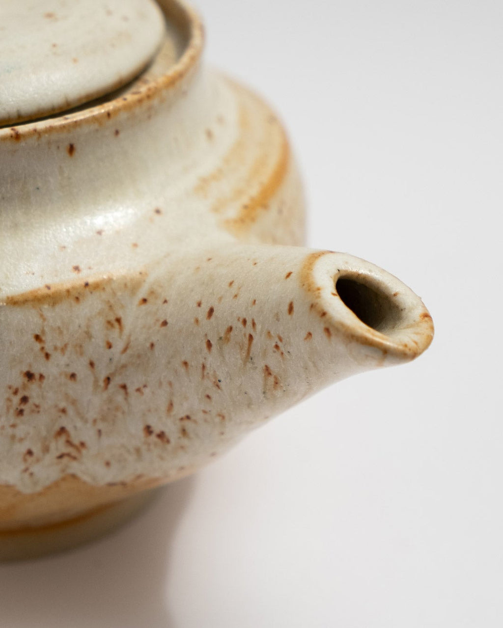 Close-up of a ceramic teapot with a textured surface on a light background