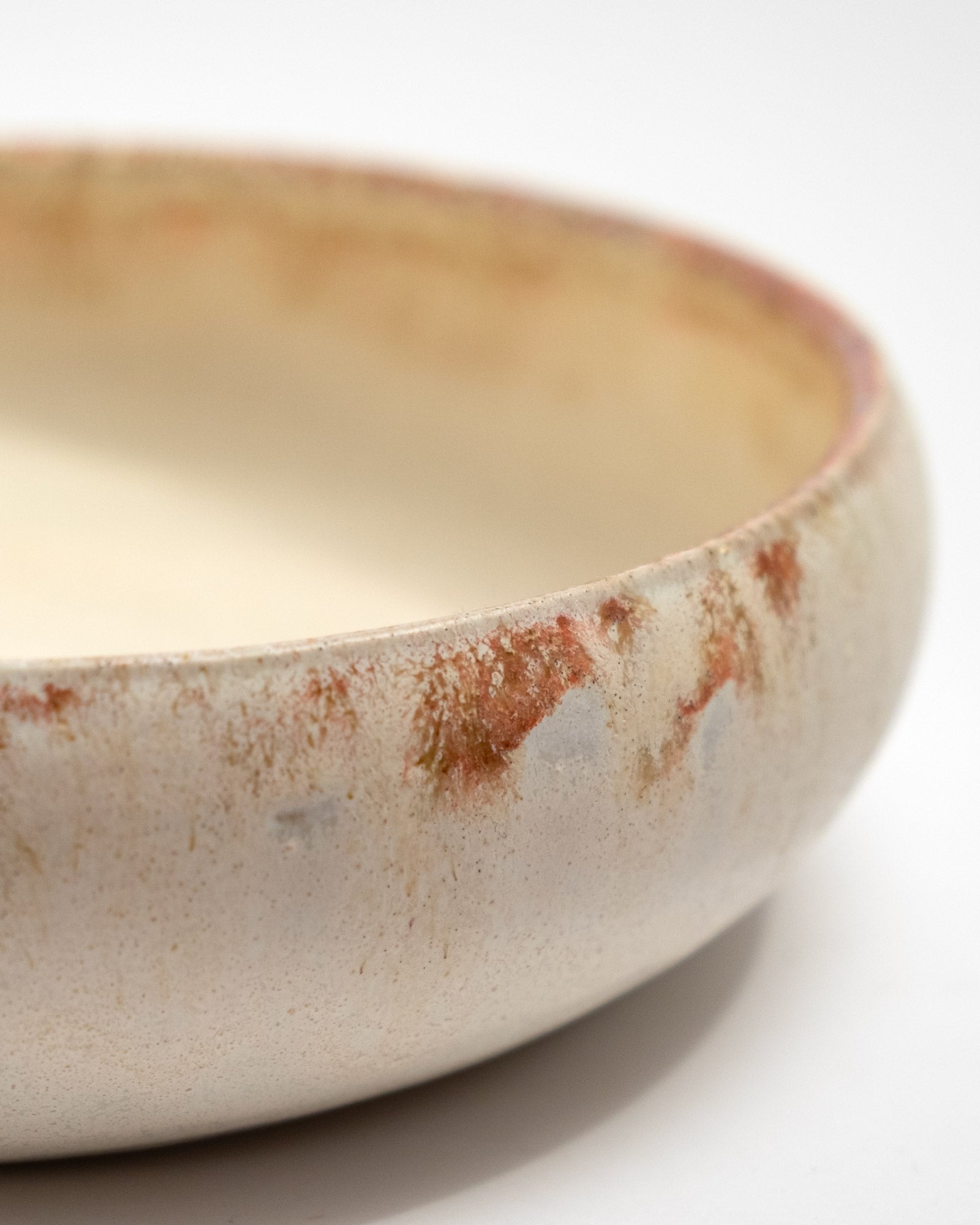 Closeup of ceramic bowl with a rustic finish on a white background, handmade in Italy