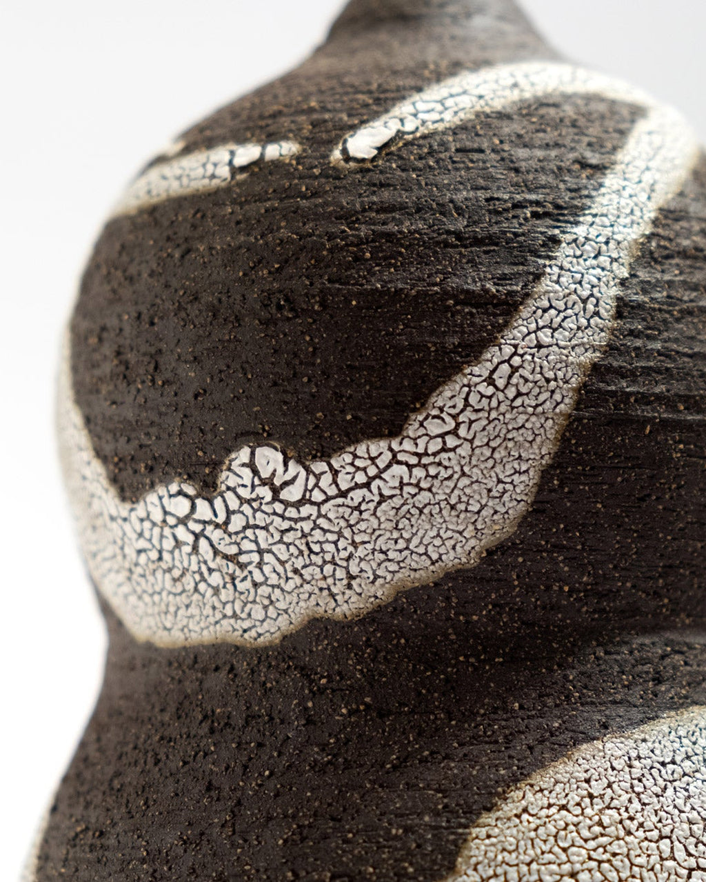 Close-up of a textured black clay and white craquele glaze