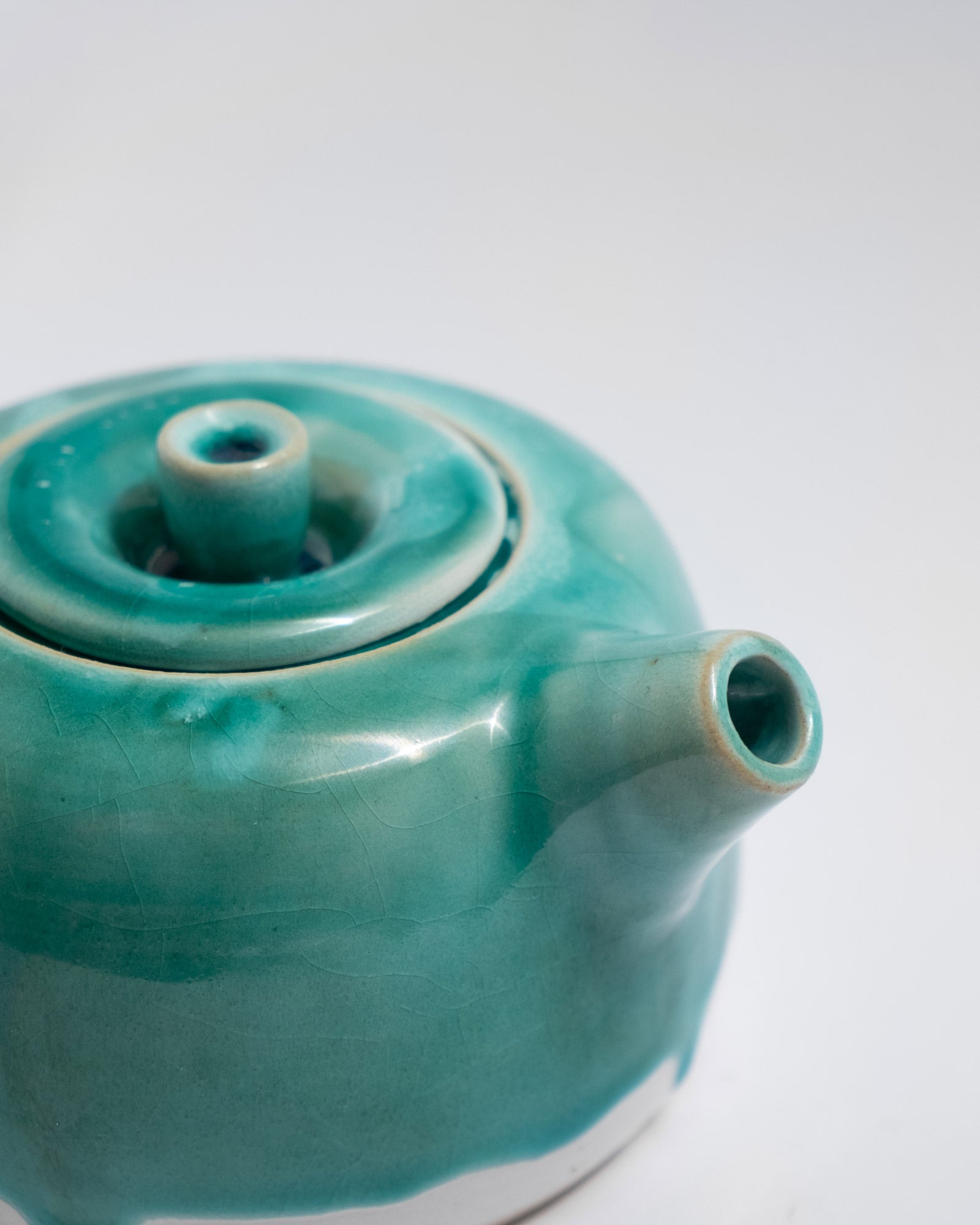 Turquoise ceramic teapot on a white background