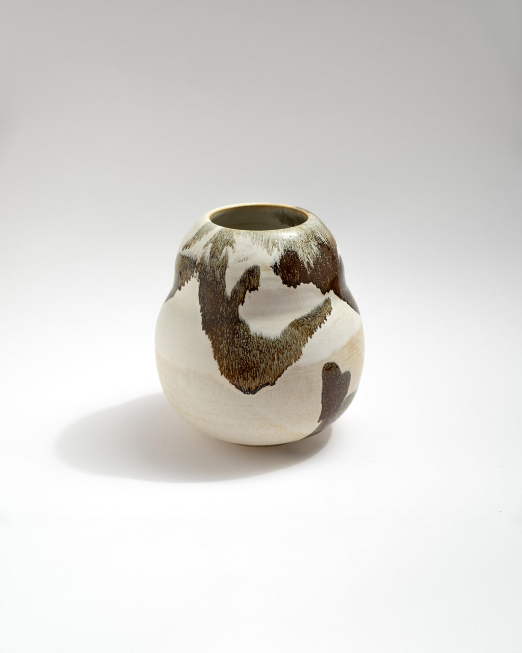 Ceramic vase with brown and white glaze on a light gray background
