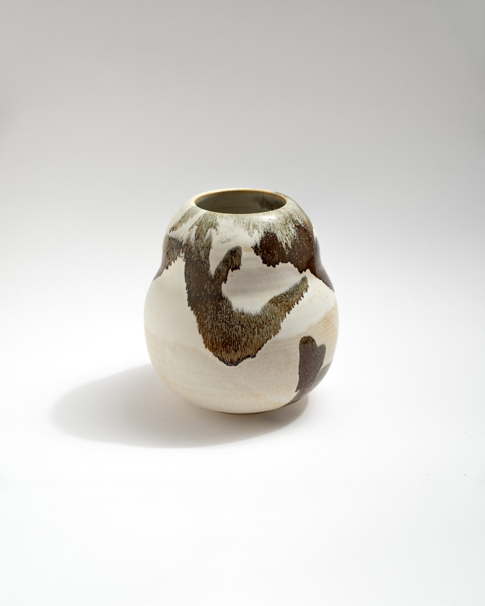 Ceramic vase with brown and white glaze on a light gray background