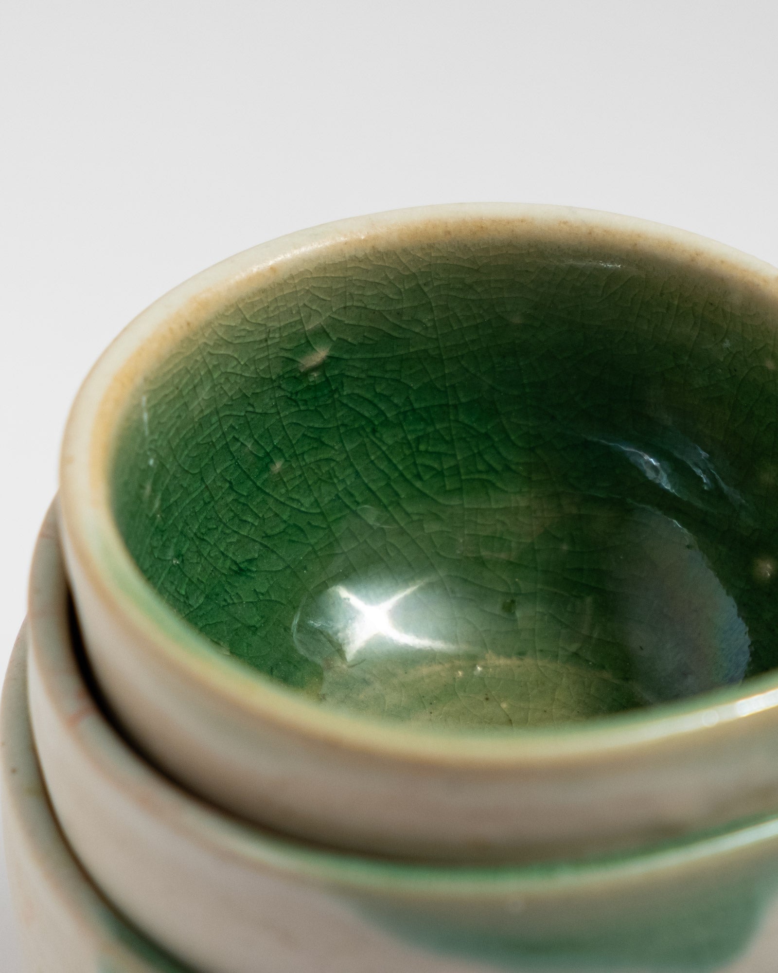 Close-up of a green ceramic bowl with a textured surface on a white background