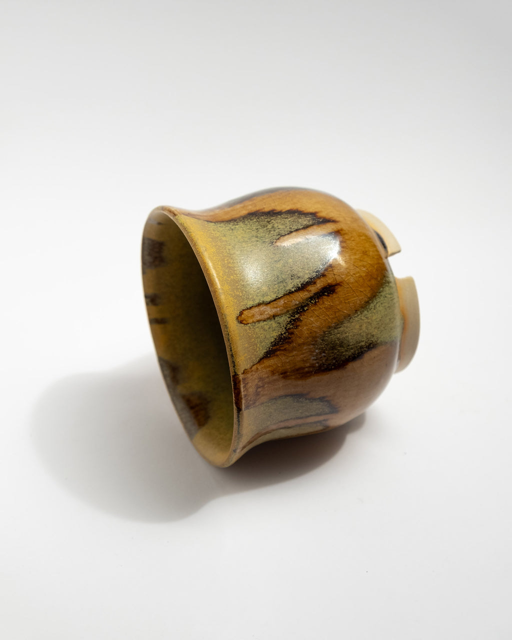 Ceramic plant pot with brown and green glaze on a white background