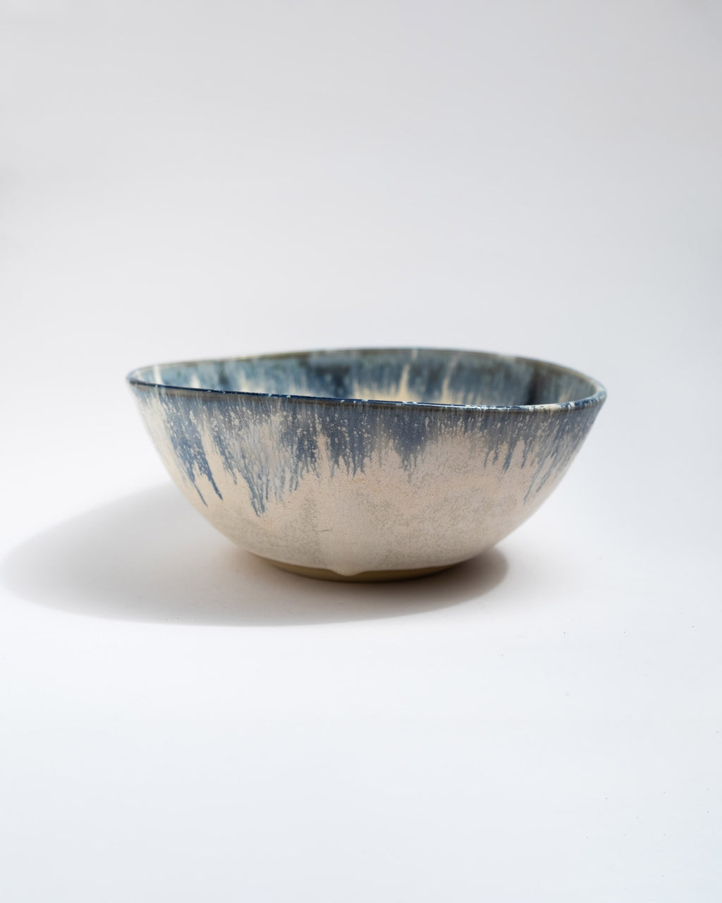 Handmade, wheel thrown ceramic bowl with blue and white glaze on a white background