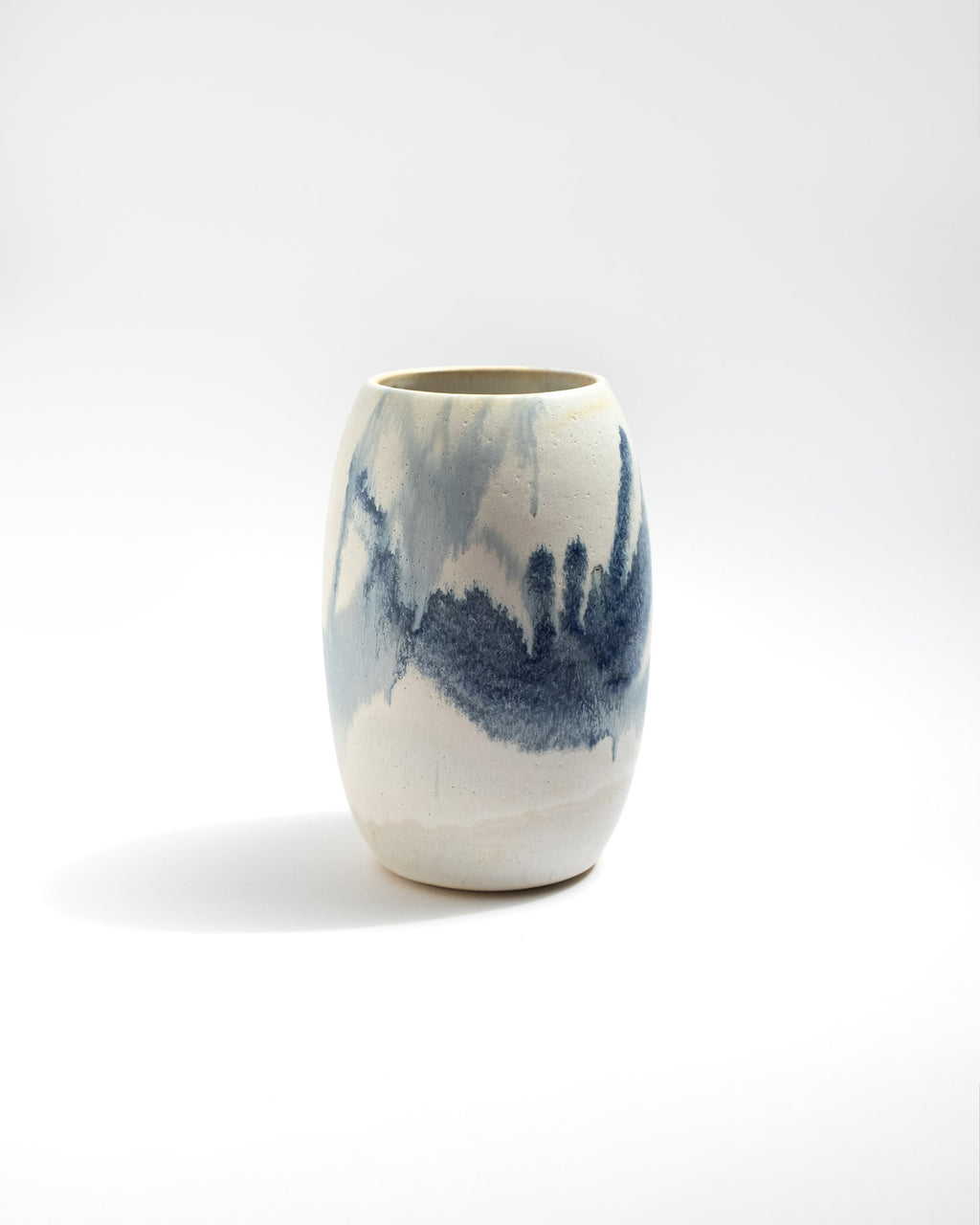 Ceramic wheel thrown vase with blue and white abstract design on a white background