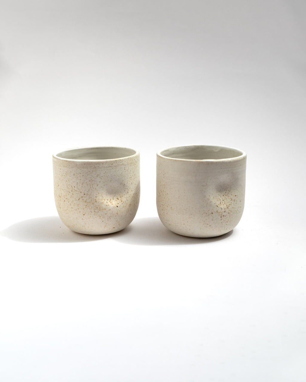 Handmade wheel-thrown stoneware cup with a speckled ivory glaze and soft cylindrical form. Minimal artisan ceramic tumbler by Malfatto Ceramics, ideal for tea, cappuccino, or everyday use.