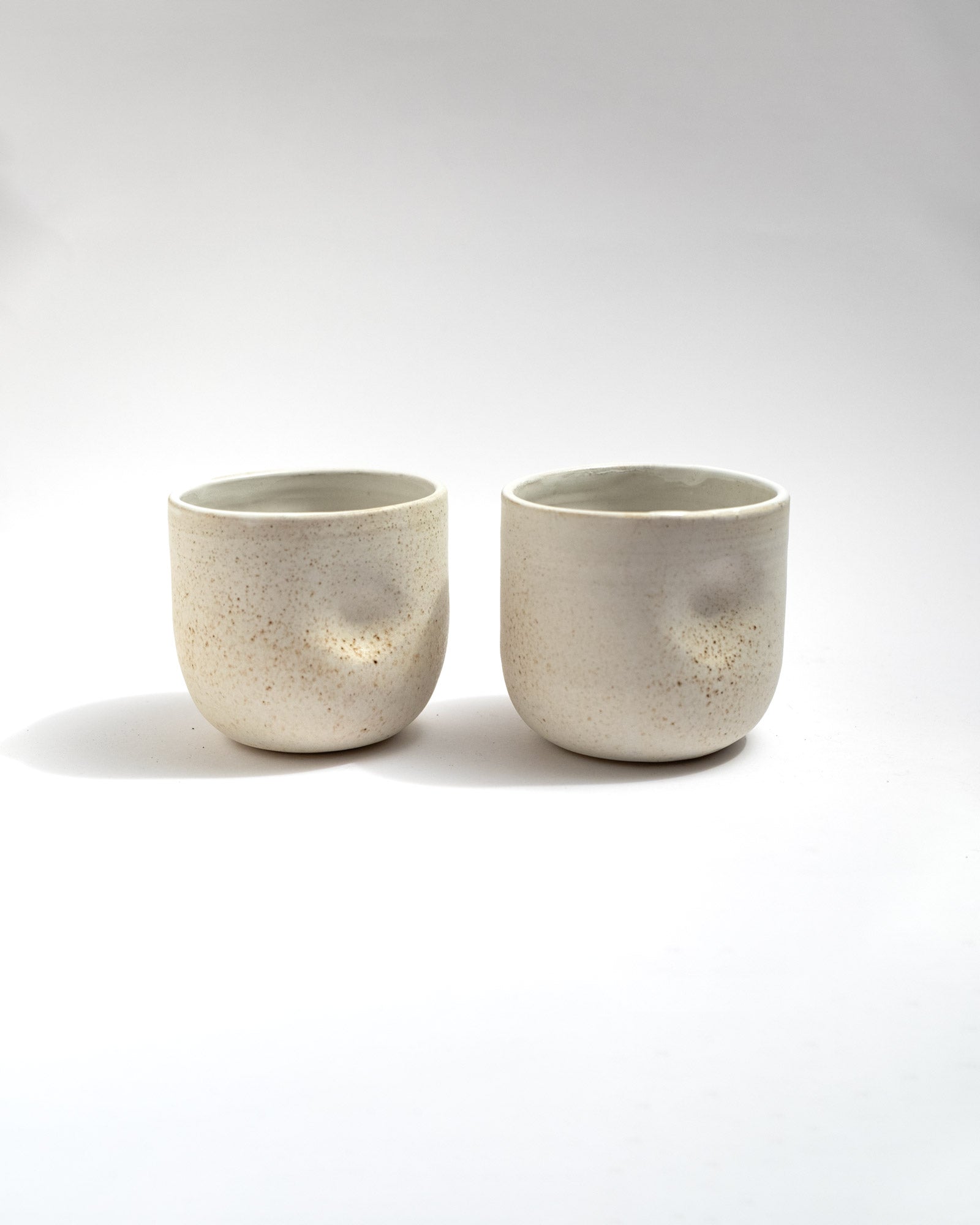 Handmade wheel-thrown stoneware cup with a speckled ivory glaze and soft cylindrical form. Minimal artisan ceramic tumbler by Malfatto Ceramics, ideal for tea, cappuccino, or everyday use.