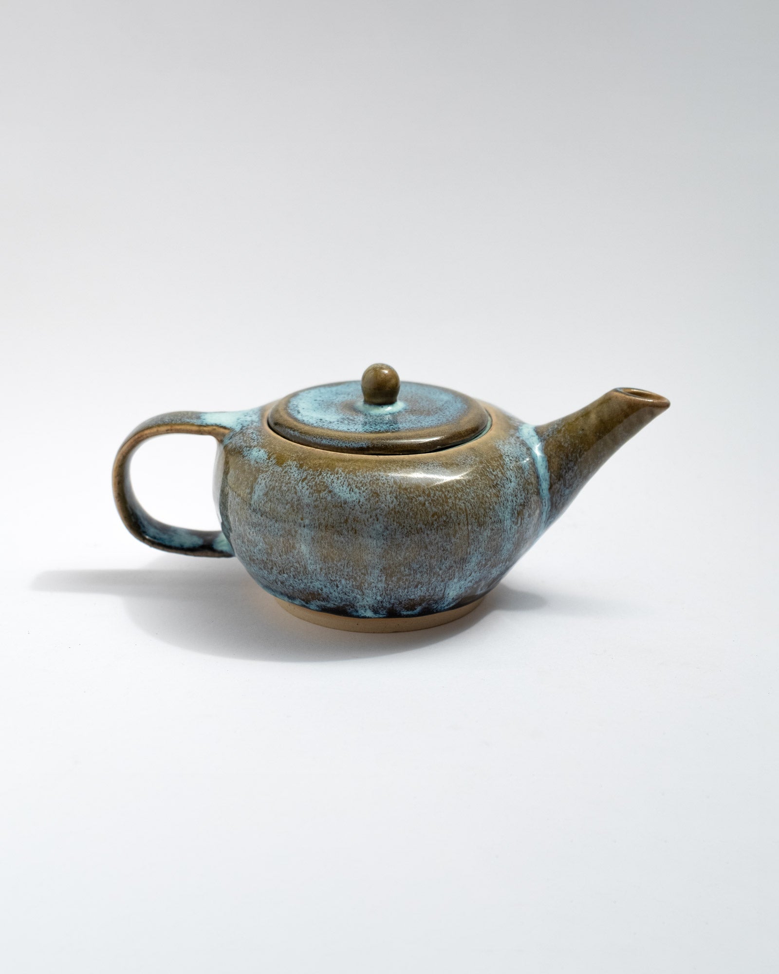 Handmade blue and brown stoneware teapot with flowing glaze and rounded body
