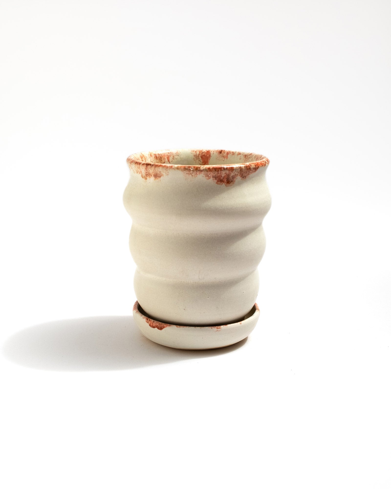 Handmade stoneware planter with matte white glaze, rust-red rim accents, and a raised foot for improved drainage. Includes matching saucer. Malfatto Ceramics.