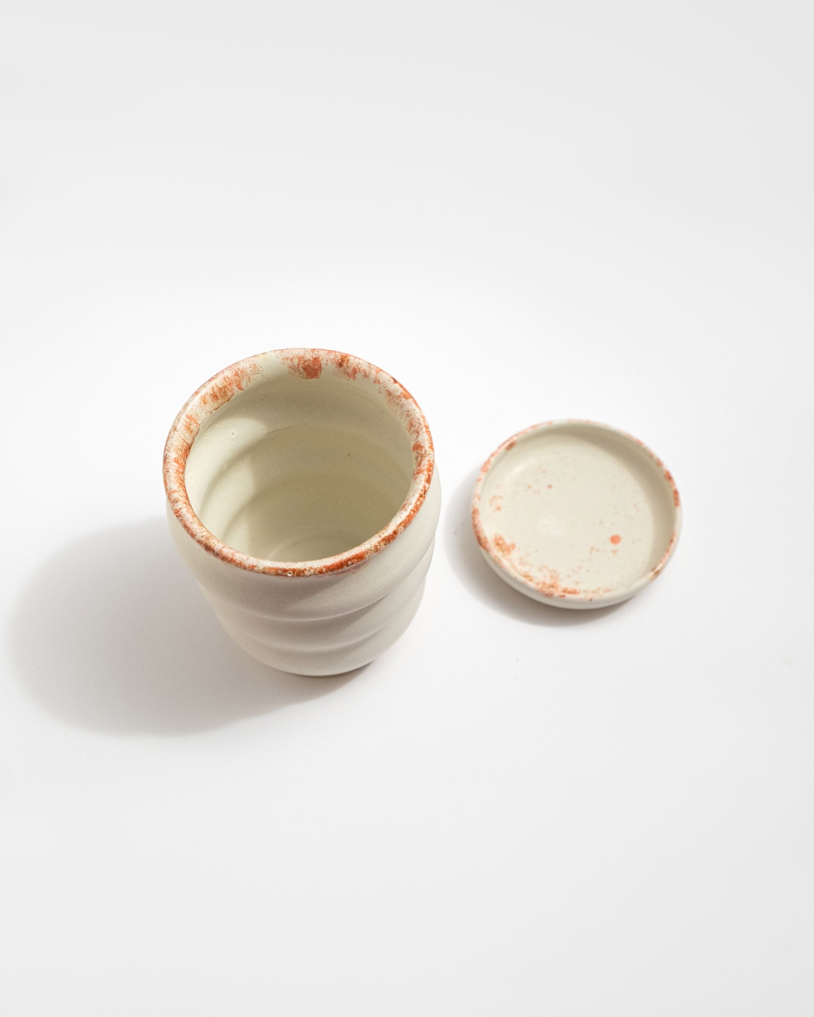 Handmade white stoneware planter with rust-red rim texture and raised foot for drainage