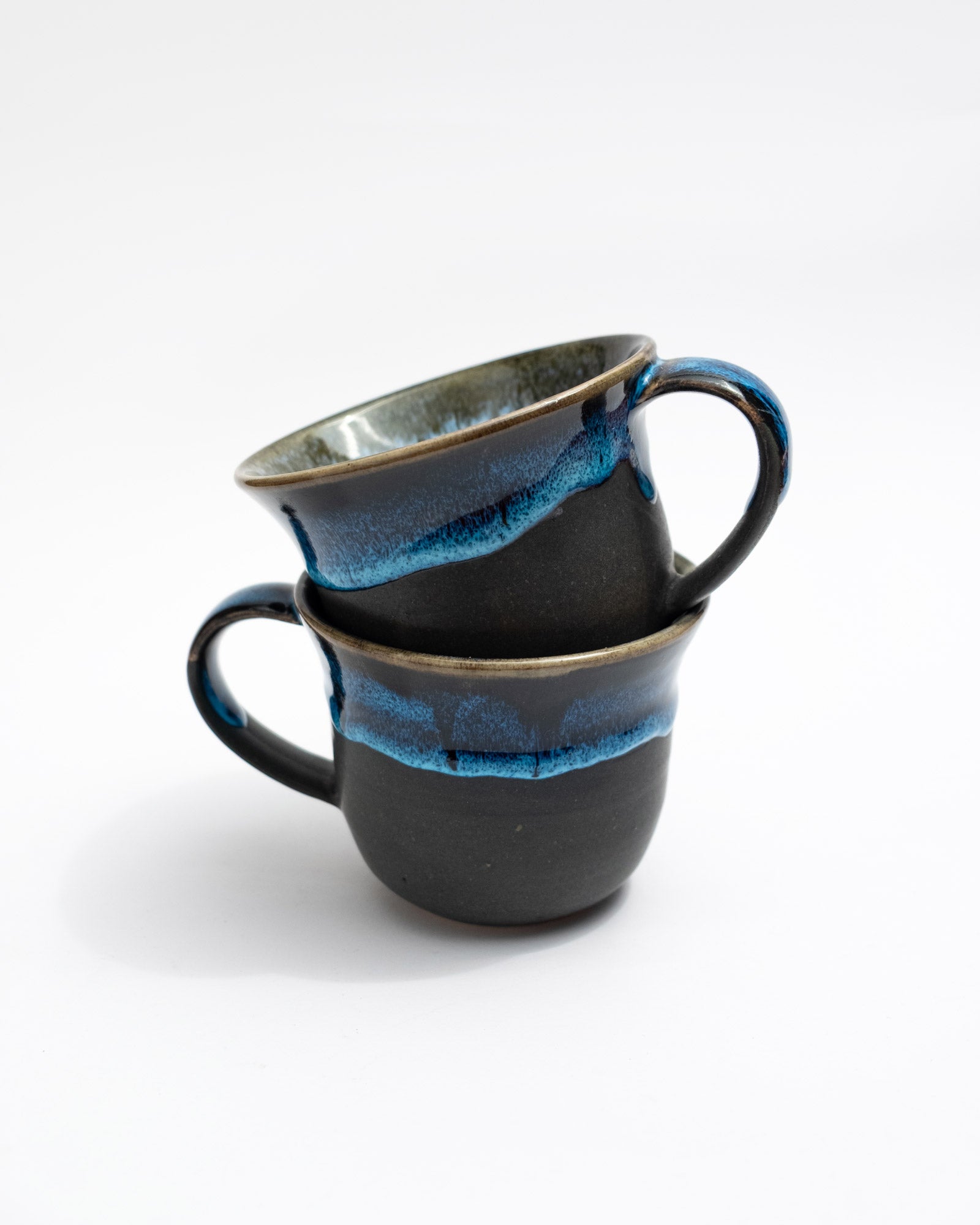Two ceramic mugs with blue interior and exterior on a white background