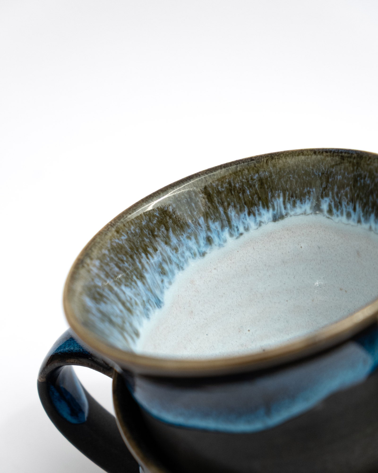 Ceramic cup with a flowing glaze and handle on a white background