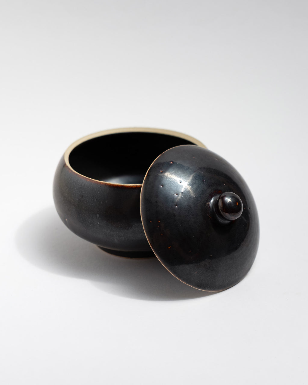 Black ceramic jar with a lid on a white background, handmade in Italy