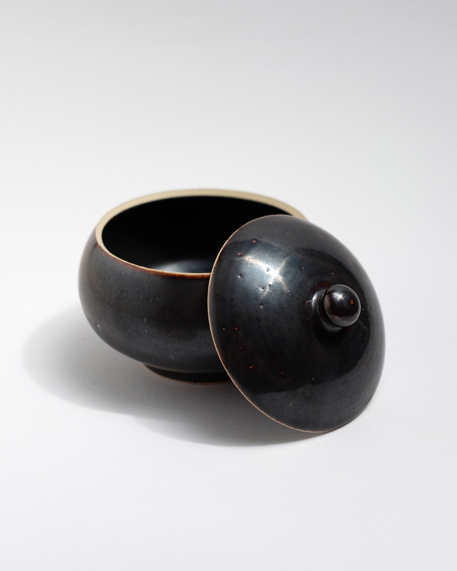 Black ceramic jar with a lid on a white background, handmade in Italy