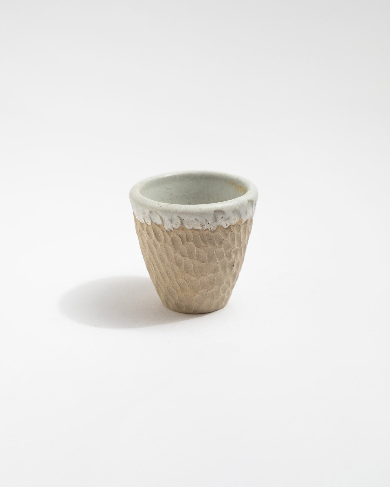 Small ceramic cup with textured surface on a white background