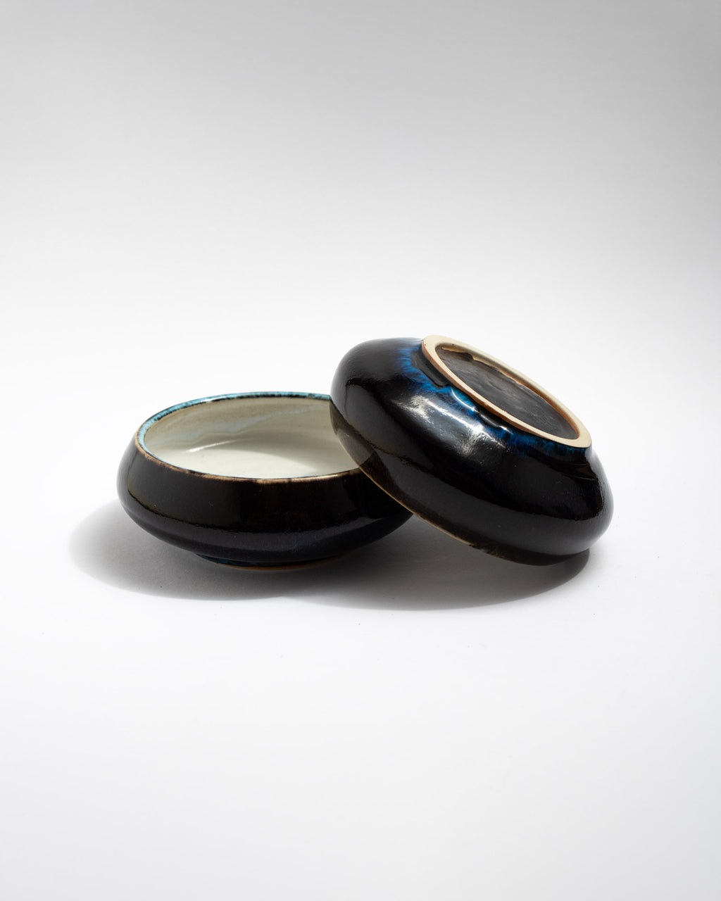 Handmade wheel-thrown small stoneware bowl with white interior, glossy dark exterior, and turquoise rim detail. Minimal artisan bowl by Malfatto Ceramics.