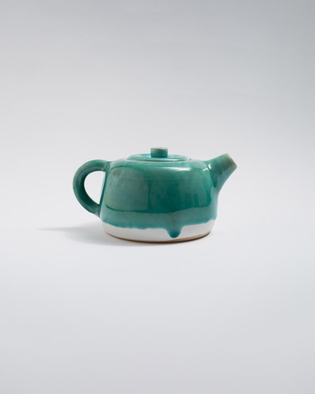 Teal ceramic teapot on a white background