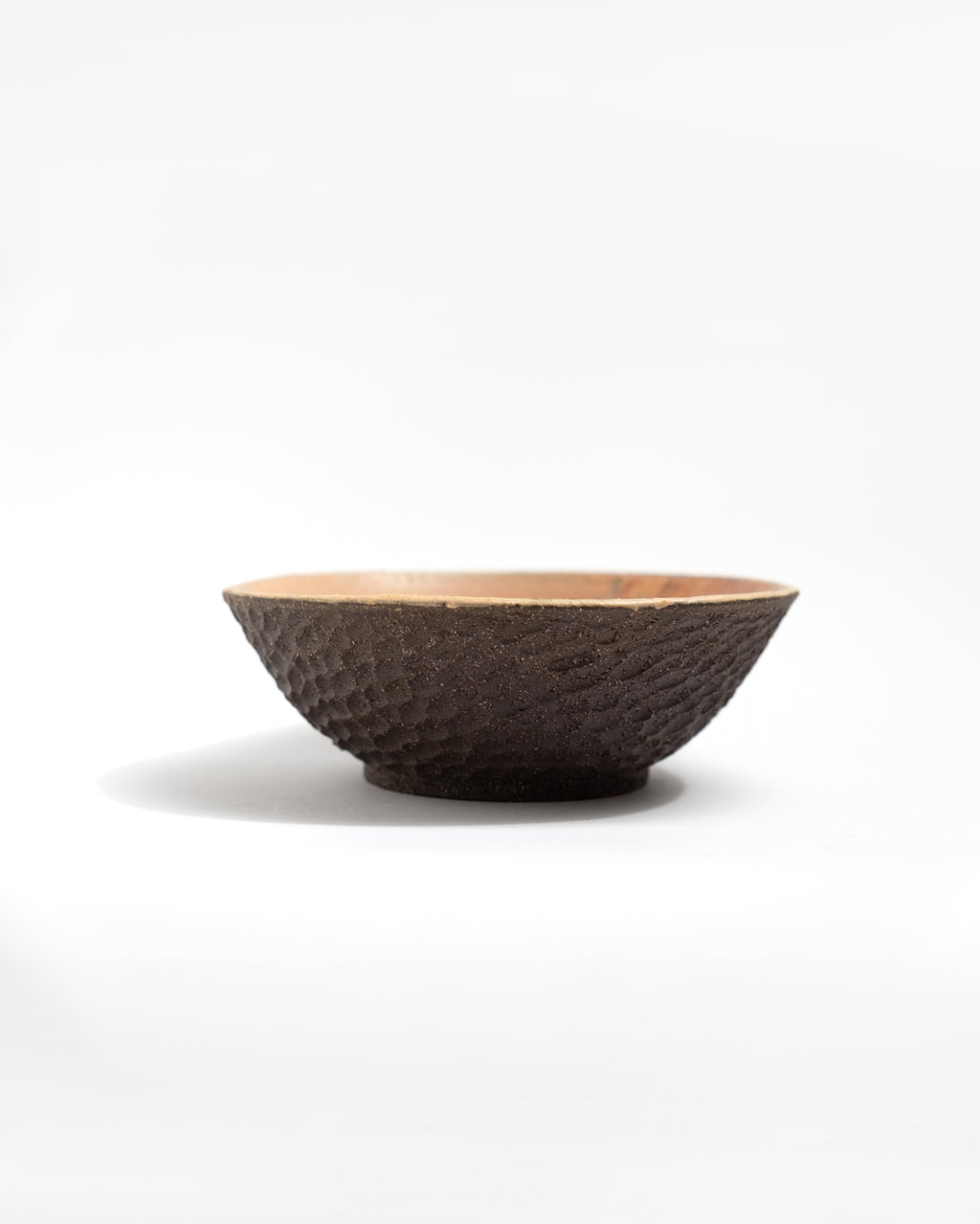 Textured ceramic black clay bowl on a white background