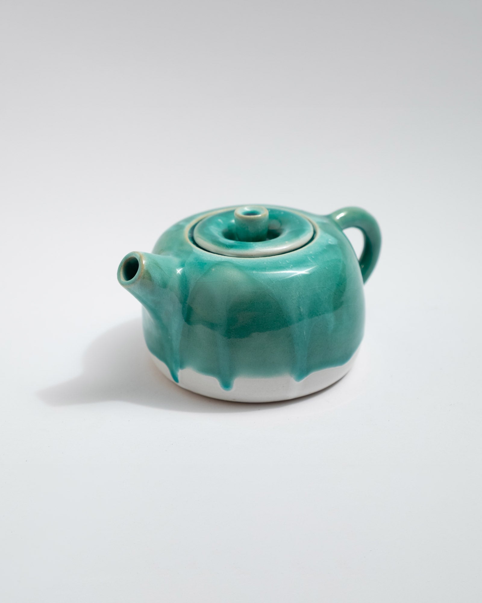 Turquoise ceramic teapot on a white background, handmade in Italy