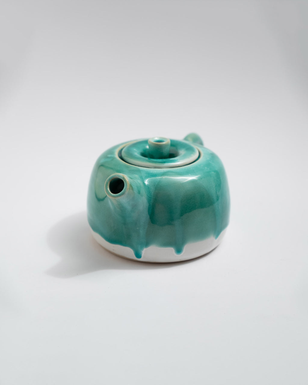 Turquoise ceramic teapot on a white background