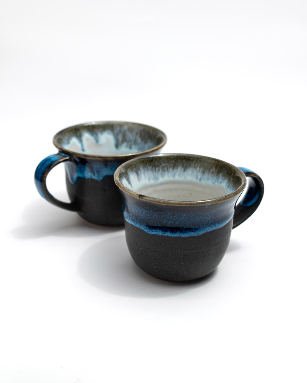 Two ceramic mugs with blue interior and exterior on a white background
