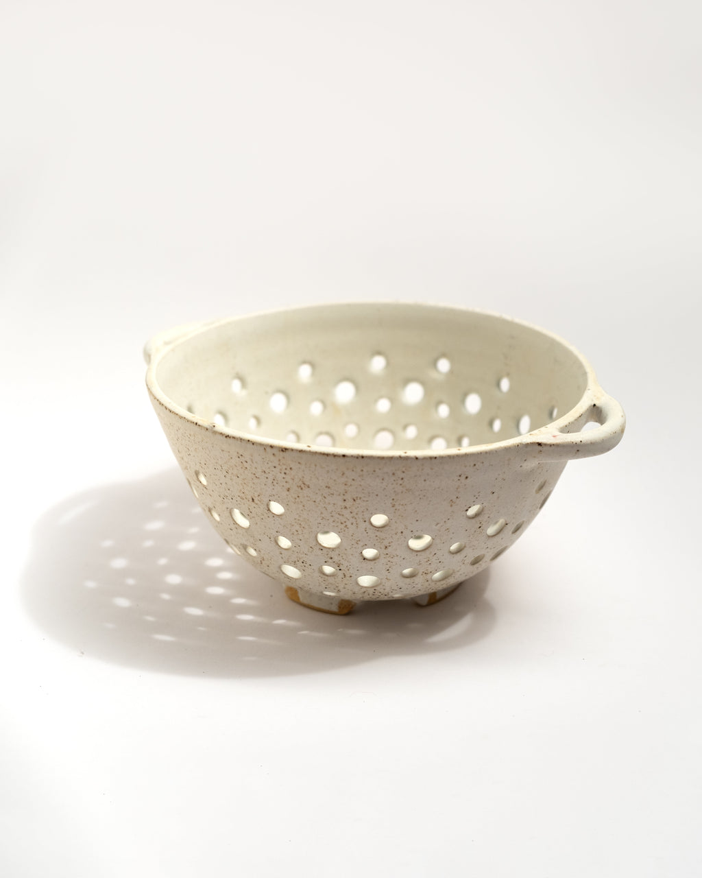 White ceramic colander with holes on a white background