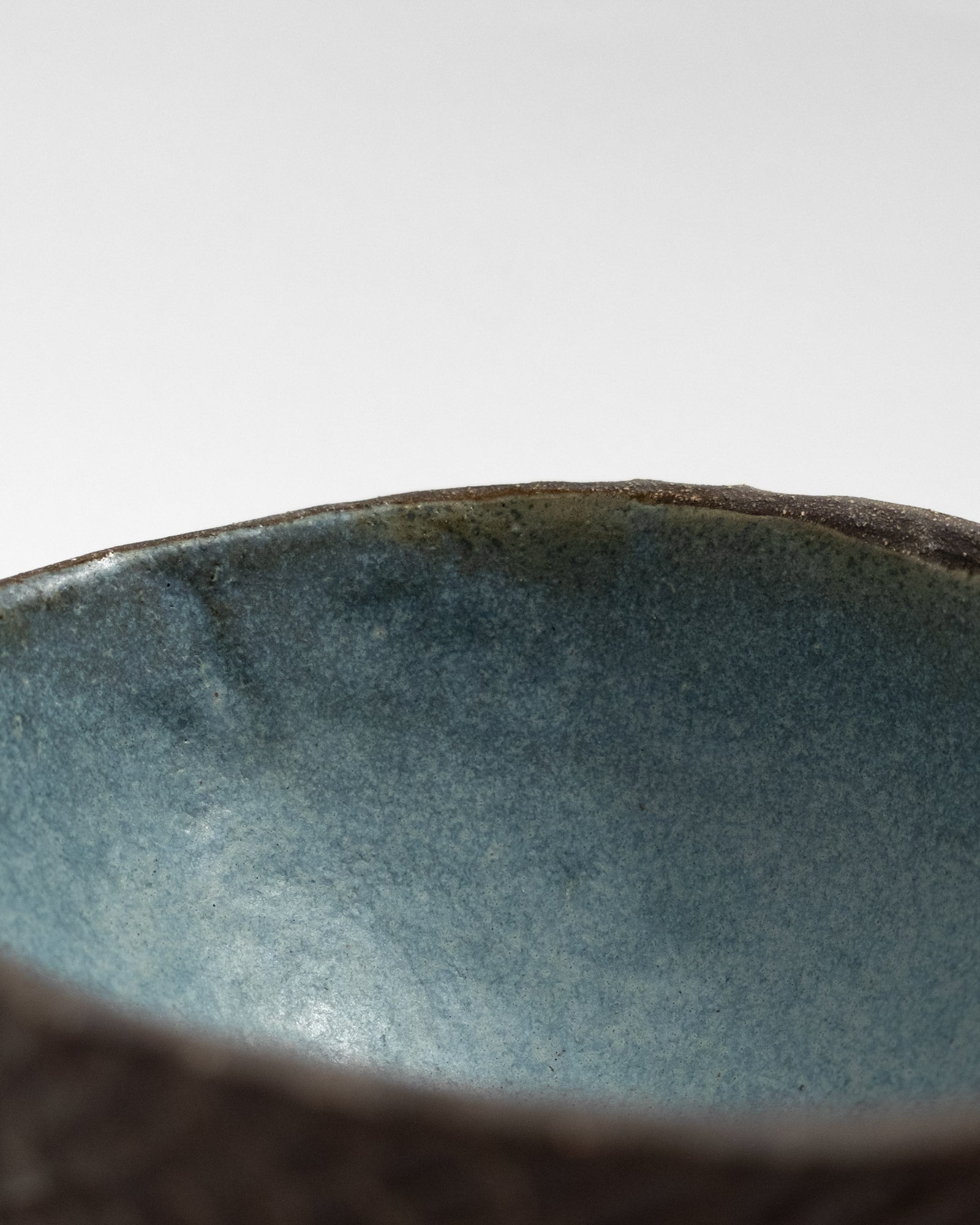 Hand-textured black clay bowl with scale-like surface and blue glazed interior, handmade in Italy