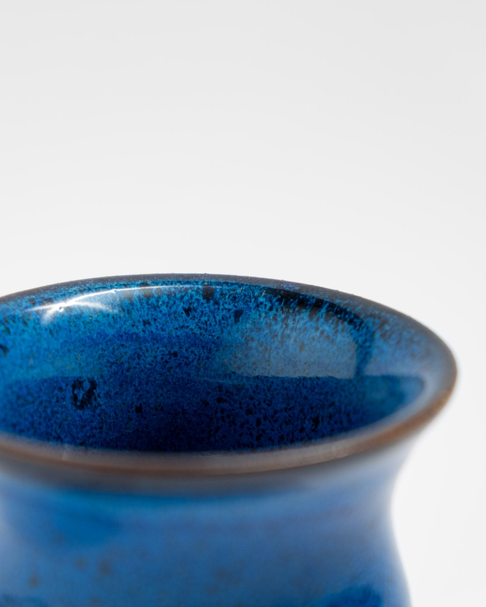 Small handmade blue ceramic planter with curved shape and matching saucer