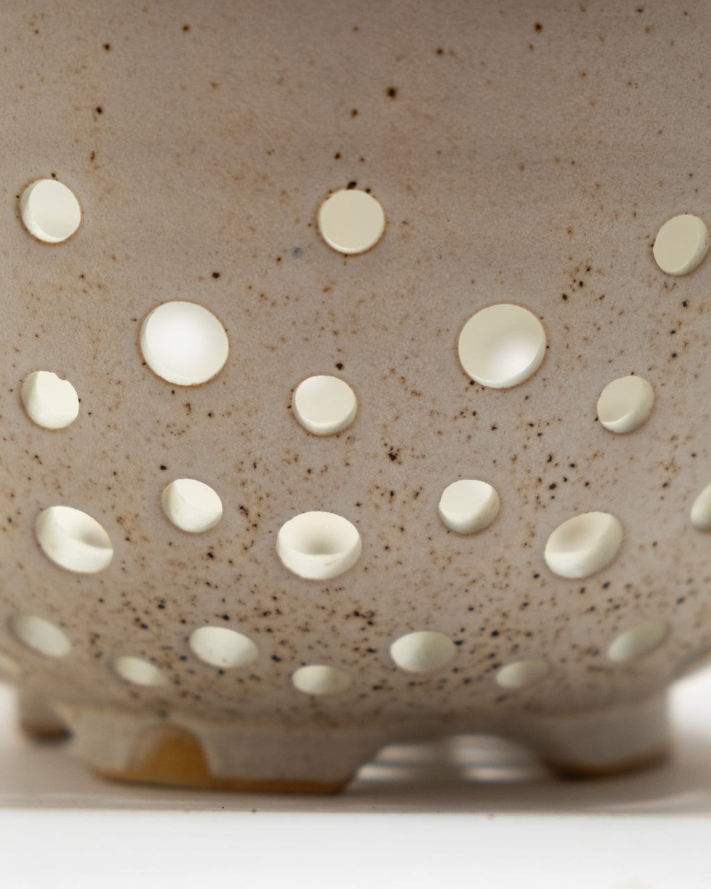 Speckled ceramic colander  on a white background