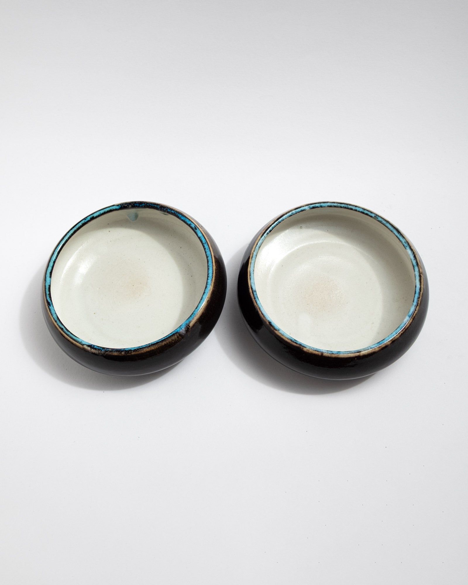 Handmade wheel-thrown small stoneware bowl with white interior, glossy dark exterior, and turquoise rim detail. Minimal artisan bowl by Malfatto Ceramics.