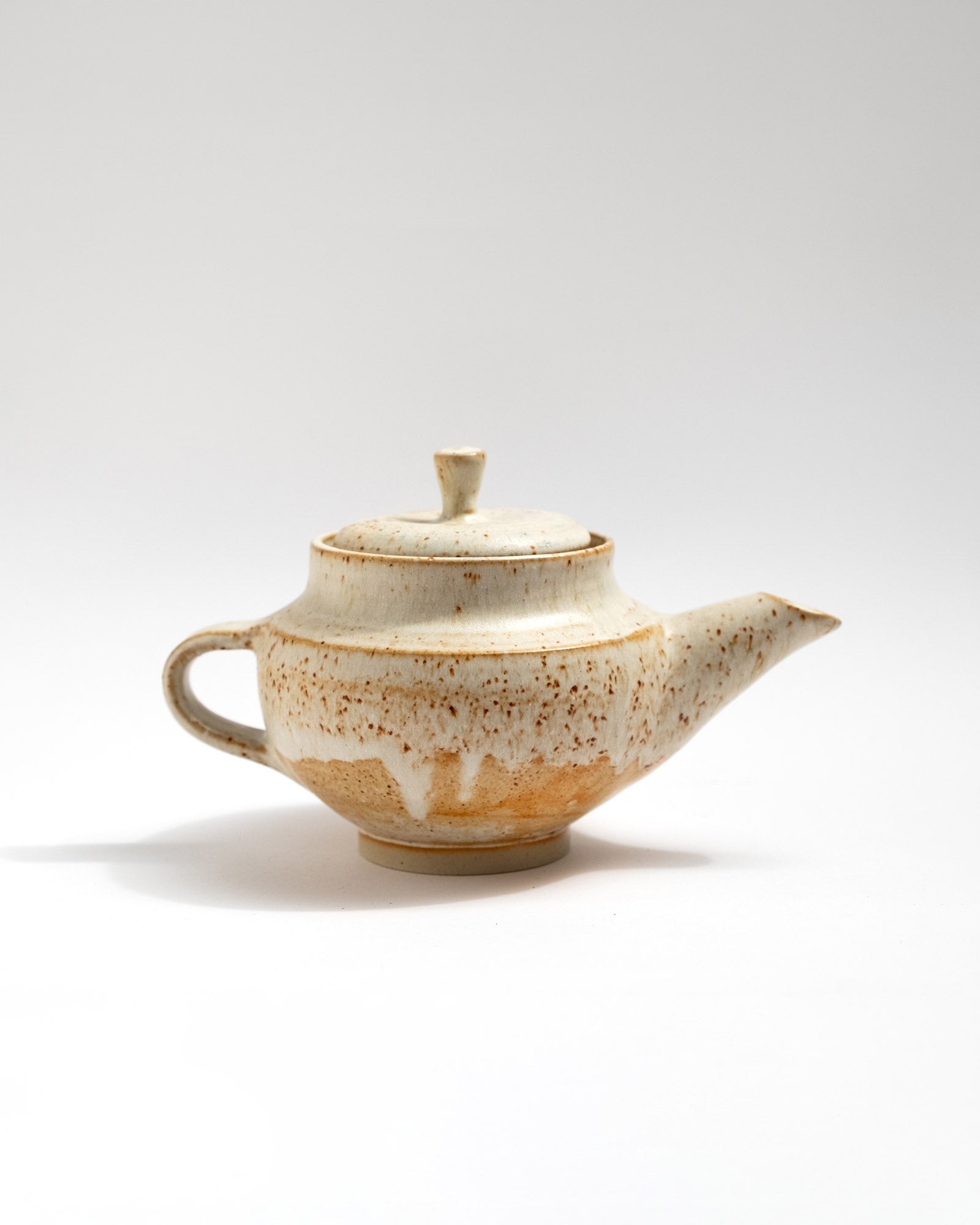 Ceramic handmade teapot with speckled glaze on a white background