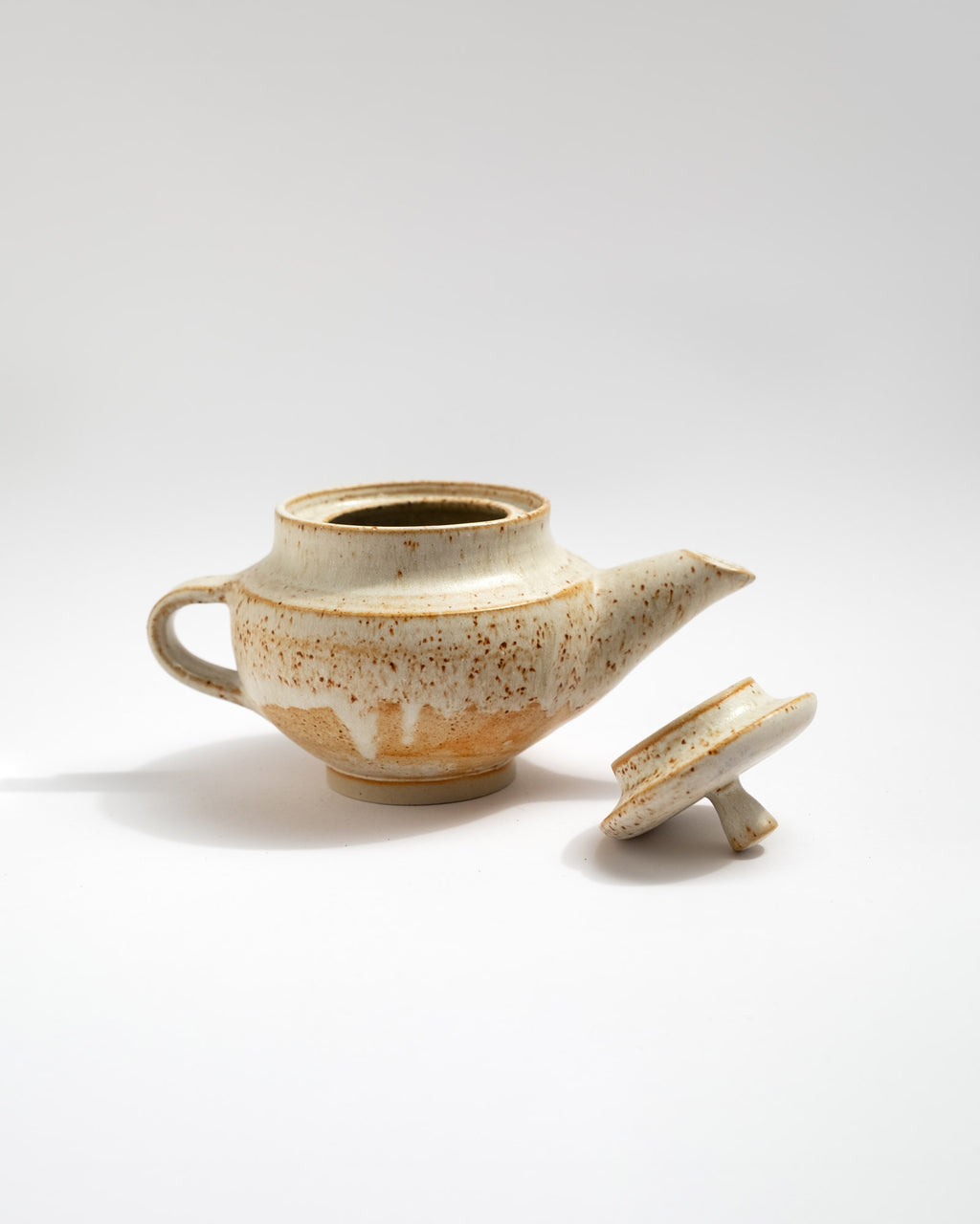 Ceramic teapot with speckled glaze on a white background