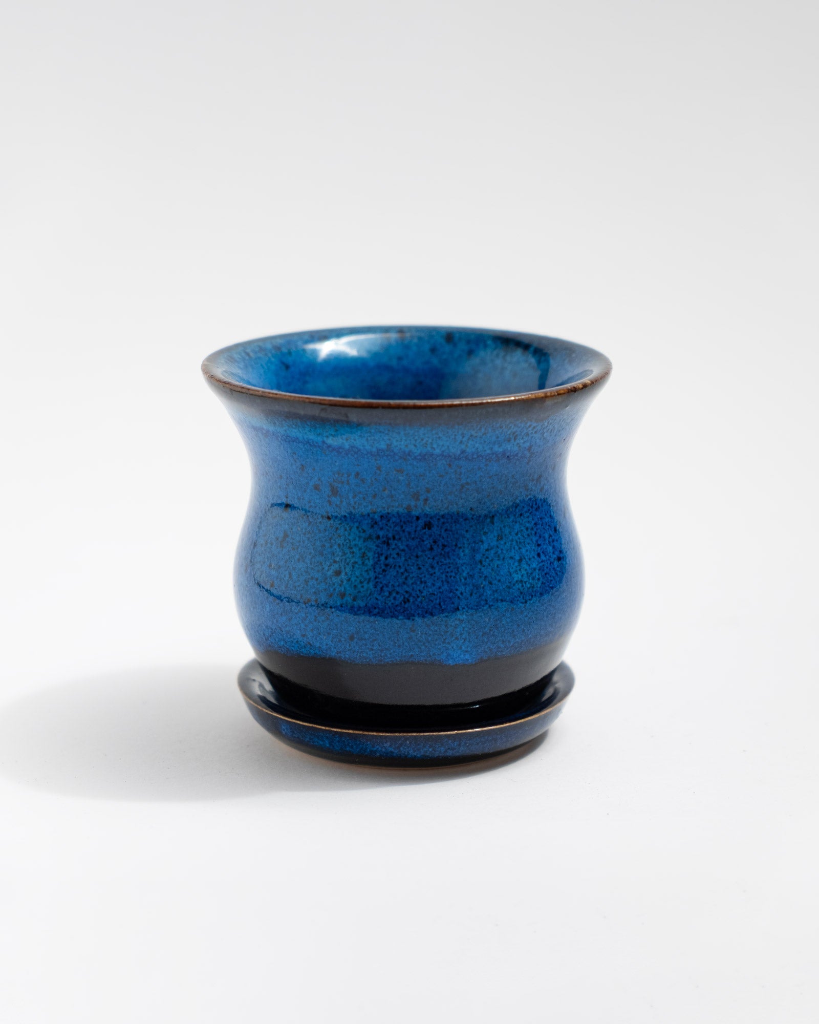 Small handmade blue stoneware planter with curved shape and matching saucer