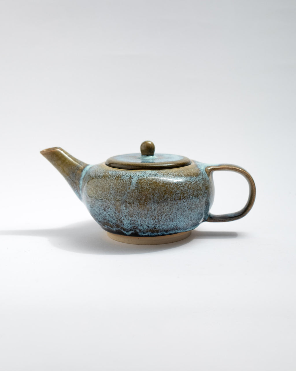 Handmade blue and brown stoneware teapot with flowing glaze and rounded body